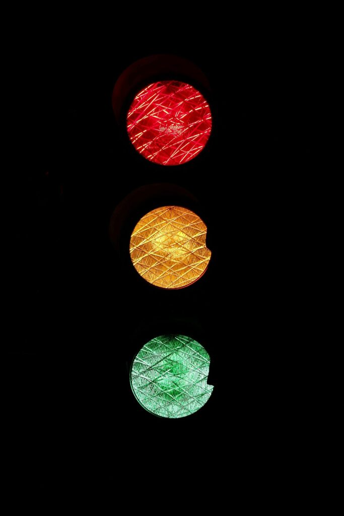 Vivid image of red, yellow, and green traffic lights against a dark background.