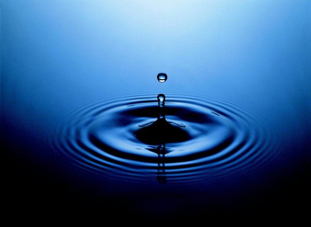 Stunning close-up of a water drop creating ripples on a serene blue surface.